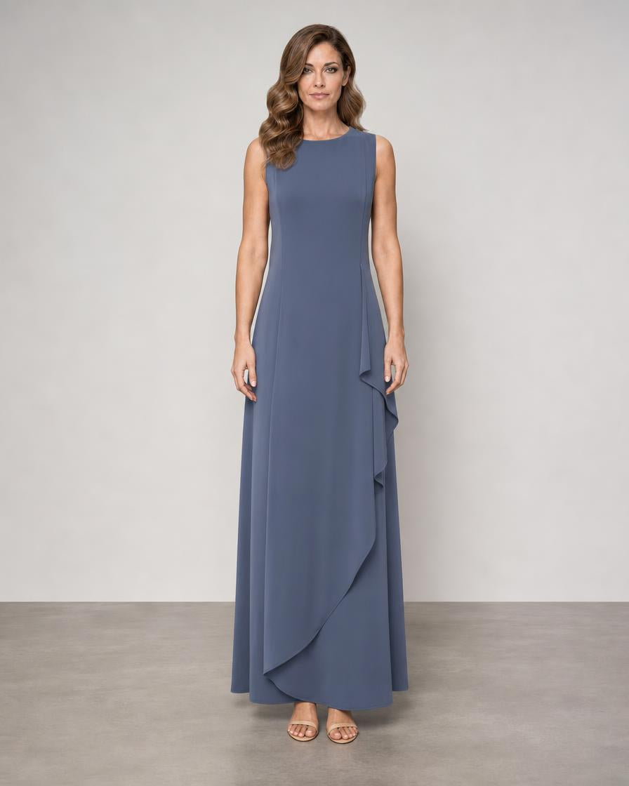 A woman modeling a sleeveless, floor-length blue-gray dress with a round neckline and layered ruffle detail along the side, standing against a neutral studio backdrop.