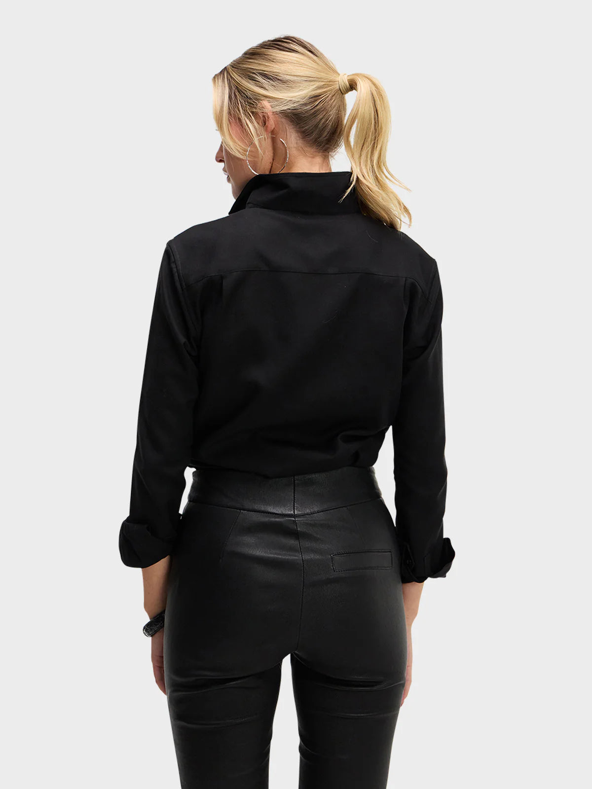 Person wearing a black jacket and black pants on a white background