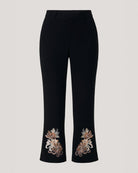 Black cropped trousers with ornate floral embroidery near the hem, shown against a light gray background.