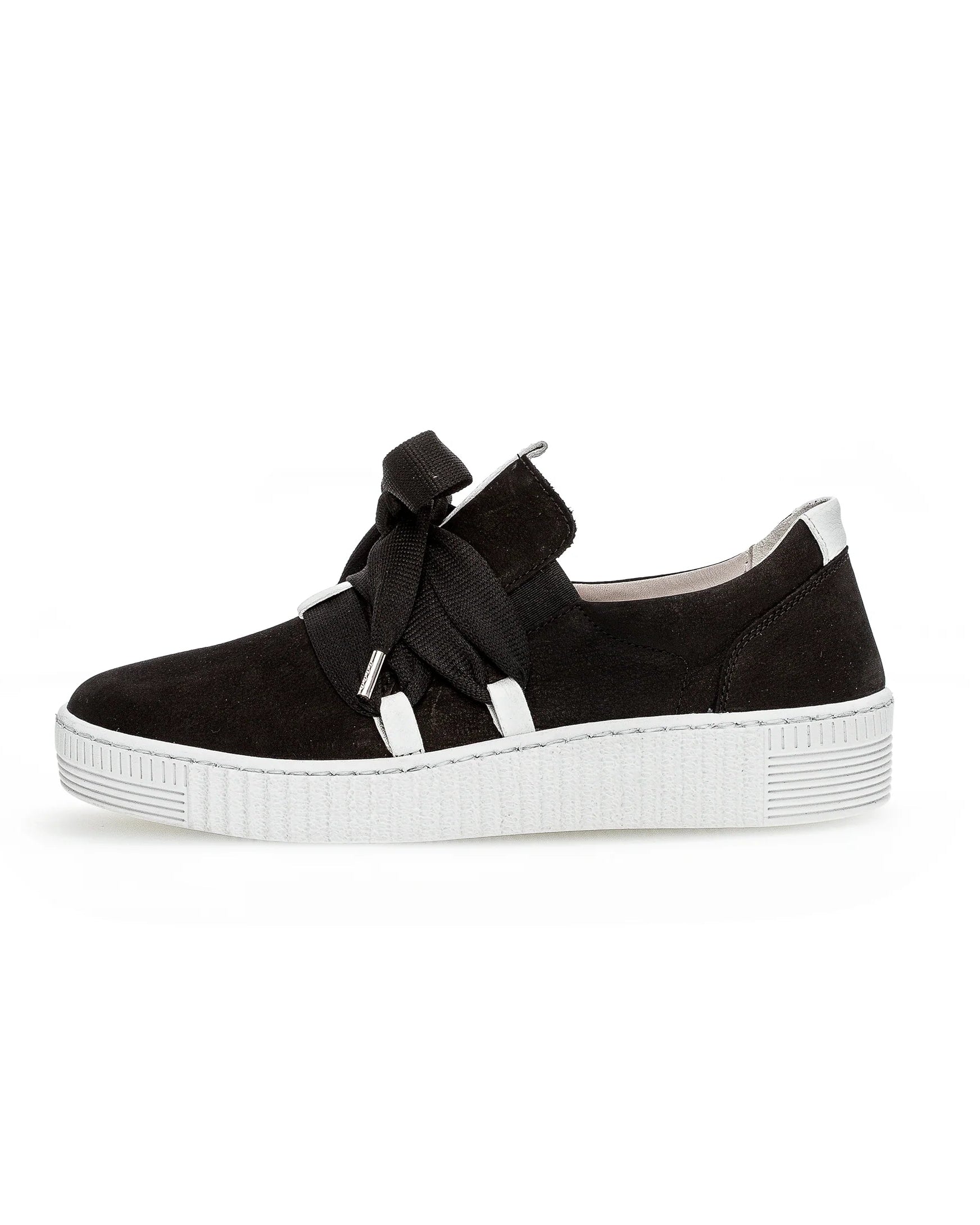A black suede slip-on sneaker with a thick white platform sole, featuring a decorative black ribbon bow across the front and white strap details.