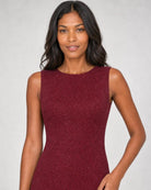 A woman modeling a sleeveless, bodycon dress in a textured burgundy fabric against a light gray studio background.